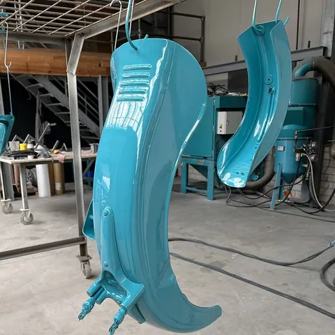 Kotflügel in Petrol lackiert, hängend in der Lackierkabine