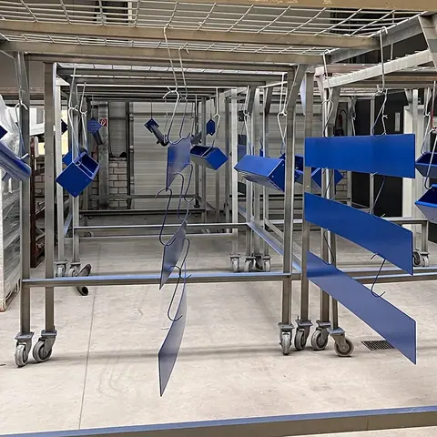 Blau lackierte Blechteile auf Wagen in der Halle